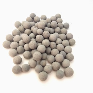 May include: A pile of small, gray, round ceramic balls. The balls are smooth and have a slightly textured surface.