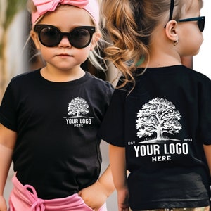 May include: Two children wearing black t-shirts with a white tree and the text "EST. 2014 YOUR LOGO HERE" on the front and back. The shirts are a blank canvas for customisation.
