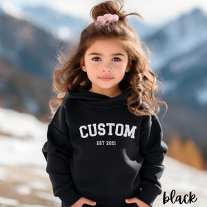 May include: Black hooded sweatshirt with the text "CUSTOM EST 2021" in white.