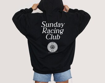 Puede incluir: Sudadera con capucha negra con el texto "Sunday Racing Club" y un logotipo de neumático estilizado en la parte posterior.