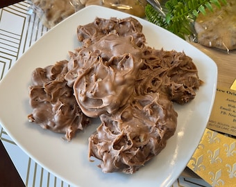 Peut inclure: Gros plan d'une assiette blanche avec plusieurs morceaux de pralines au chocolat et aux noix de pécan. Les pralines sont de couleur brun clair et ont un motif en spirale. Les pralines sont disposées en tas sur l'assiette.