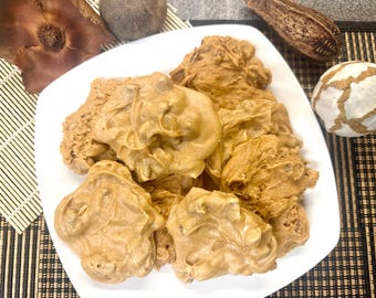 Peut inclure: Une assiette blanche remplie de pralines aux noix de pécan. Les pralines sont de couleur brun clair et ont une finition lisse et brillante.