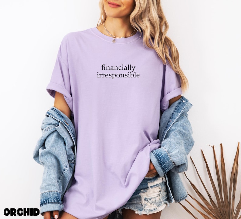 May include: A light purple t-shirt with the text "financially irresponsible" printed on the front.