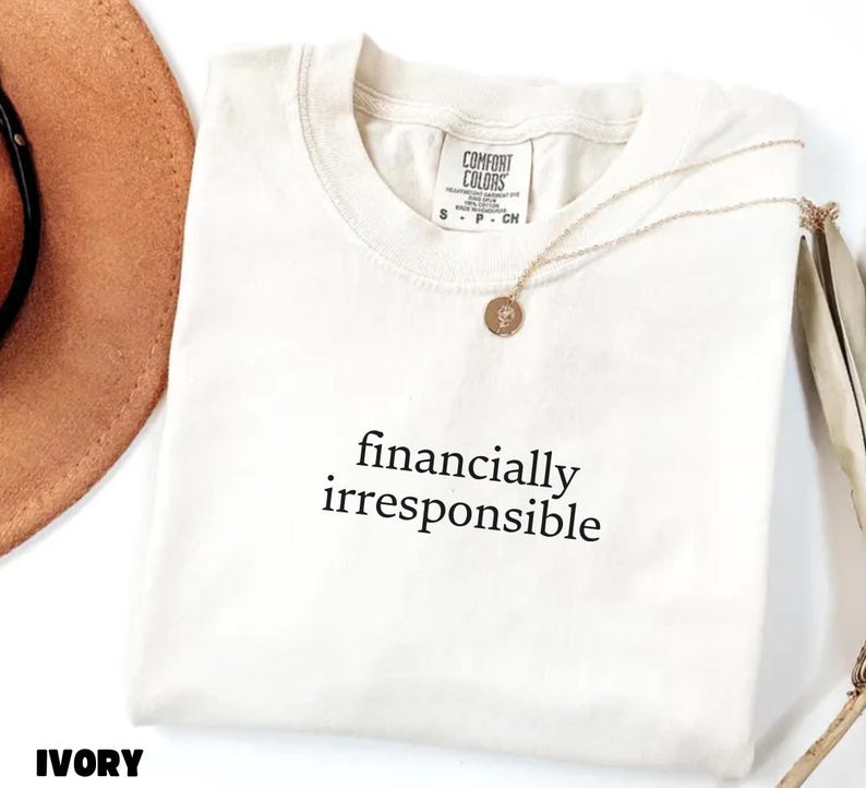 May include: Ivory t-shirt with the text "financially irresponsible" printed in black.
