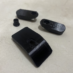 Puede incluir: Tres piezas de plástico negro con agujeros. Las piezas son de diferentes formas y tamaños.