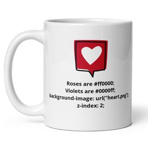 Peut inclure: Mug en céramique blanche avec une anse. Le mug présente un carré rouge avec un cœur blanc et le texte "Roses are #ff0000; Violets are #0000ff; background-image: url("heart.png"); z-index: 2;"