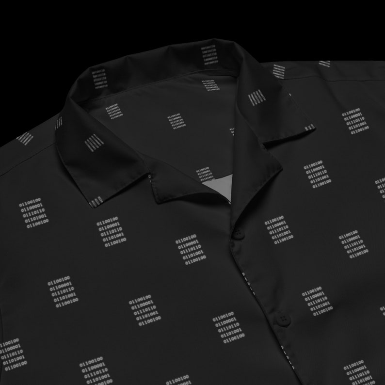 Puede incluir: Una camisa negra de manga corta con botones y un patr&oacute;n repetido de c&oacute;digo binario blanco. La camisa tiene cuello y cierre de botones.