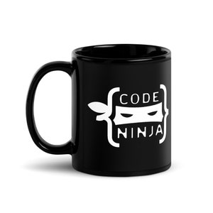 May include: Black ceramic coffee mug with a white graphic of a ninja wearing a mask inside of code brackets. The text "CODE NINJA" is written below the ninja.