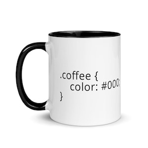 May include: White ceramic mug with a black rim and handle. The mug has black text that reads '.coffee { color: #000; }'.