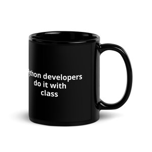 K&ouml;nnte beinhalten: Schwarze Kaffeetasse mit wei&szlig;em Text, der "Python developers do it with class" lautet.