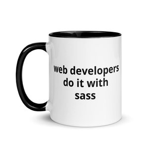 May include: White coffee mug with a black rim and handle. The mug has the text "web developers do it with sass" printed on it.