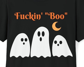 May include: Black t-shirt featuring the orange text "Fuckin' "Boo"" above three white ghost figures and a crescent moon. The ghosts have black eyes and are arranged in a row. A Halloween-themed graphic tee.