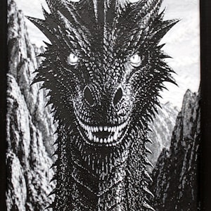 May include: Black and white dragon art print. The dragon has sharp teeth, glowing eyes, and a detailed, textured appearance. The background shows a mountain landscape. The artwork is framed in a black frame.