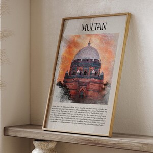 May include: A framed print with the word "MULTAN" at the top, depicting a detailed illustration of a domed building in red and orange hues. The print is on a wooden shelf, alongside decorative vases.