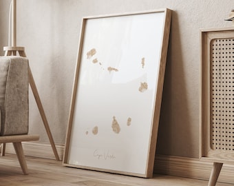 May include: A framed print of a minimalist watercolor painting of Cape Verde islands in shades of brown and white, hanging on a beige wall above a wooden cabinet with a woven rattan door.
