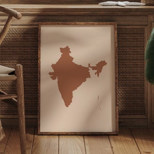 Może przedstawiać: Wydruk w ramie przedstawiający brązowy zarys Indii na jasnobeżowym tle. Wydruk wisi na ścianie w drewnianej ramie.