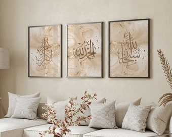 May include: Three framed prints with gold calligraphy on a beige background. The prints are hung on a light beige wall above a white couch with pillows.
