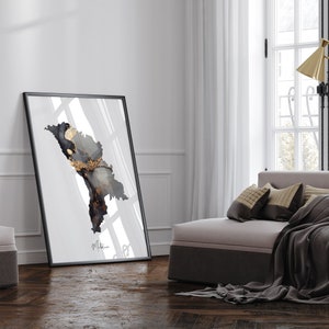 May include: A black framed print with a white background and a black and gold abstract design. The print is hanging on a white wall in a modern living room.