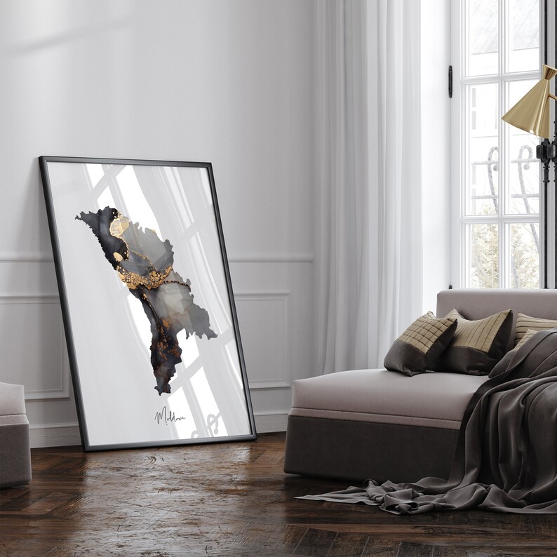 May include: A black framed print with a white background and a black and gold abstract design. The print is hanging on a white wall in a modern living room.