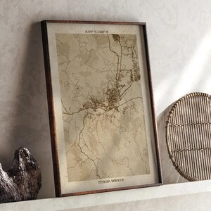 Op de afbeelding: Een ingelijste kaartafdruk van Tetouan, Marokko, in vintage stijl. De kaart toont gedetailleerde stratenplannen en geografische kenmerken in bruine tinten tegen een beige achtergrond. De lijst is donkerbruin.