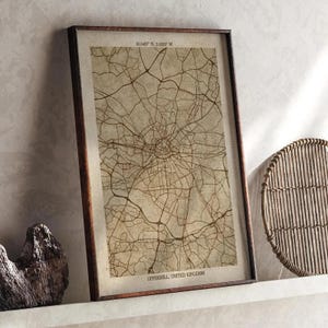 Puede incluir: Impresión enmarcada de un mapa de Uppermill, Reino Unido, en tonos sepia. El mapa muestra una red de carreteras detallada, con el texto "UPPERMILL, UNITED KINGDOM" en la parte inferior. El marco es de color marrón oscuro.