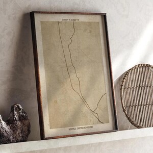 Puede incluir: Impresión enmarcada de un mapa vintage de Bootle, Reino Unido, con coordenadas en la parte superior. El mapa está en tonos sepia, con un marco de madera marrón oscuro. El texto "BOOTLE, UNITED KINGDOM" está en la parte inferior.