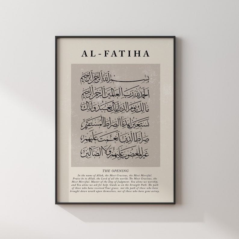 May include: A black and white print of the first chapter of the Quran, Al-Fatiha, in Arabic script. The text is framed in a black frame against a white wall. The title "Al-Fatiha" and the English translation of the text are printed below the Arabic script.