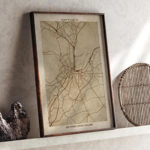 May include: A framed sepia-toned map print of Hollywood, United Kingdom. The map shows a detailed network of roads and streets. The text "HOLLYWOOD, UNITED KINGDOM" is at the bottom. The frame is dark brown.