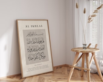 May include: A framed print of the Islamic prayer "Al-Ikhlas" in Arabic calligraphy. The text is in black on a beige background. The frame is brown wood. The print is titled "Al-Ikhlas" and "The Sincerity".