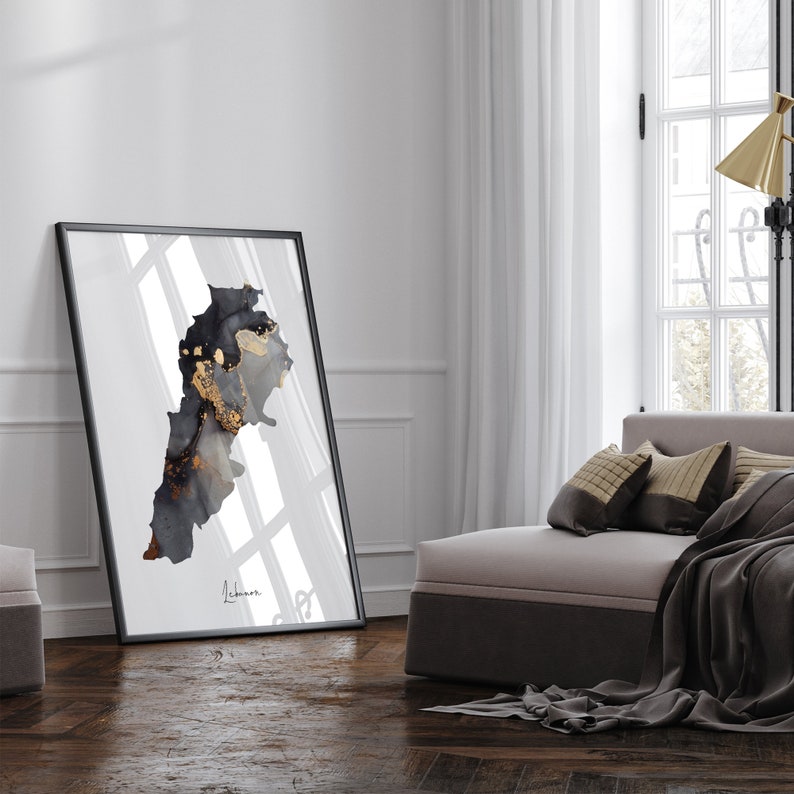 May include: A black and gold abstract art print of the country of Lebanon in a black frame. The print is hanging on a white wall in a modern living room.