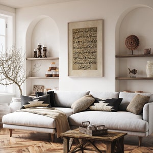 May include: A white sectional sofa with black and white patterned throw pillows in a living room setting. A framed print with Arabic calligraphy hangs on the wall above the sofa. The sofa is in front of a wooden coffee table with a woven basket on top.