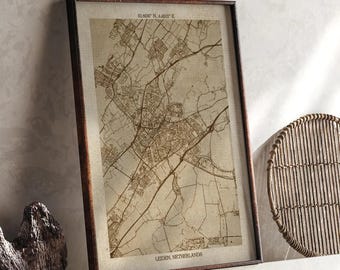 May include: Framed vintage-style map of Leiden, Netherlands, in a dark wooden frame. The map is in sepia tones, showing roads, buildings, and geographical features. Coordinates are printed at the top. The text "Leiden, Netherlands" is at the bottom.