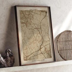 Puede incluir: Impresión enmarcada de un mapa de Halstead, Reino Unido, en tonos sepia. El mapa presenta detalles de carreteras y calles, con el texto "Halstead, United Kingdom" en la parte inferior. El marco es de color marrón oscuro.