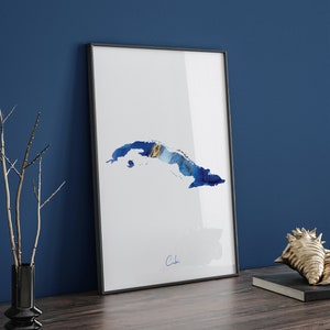 May include: A framed print of a blue and gold watercolour illustration of the island of Cuba. The print is on a white background and the word "Cuba" is written in cursive at the bottom.