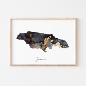 May include: A black and gold abstract art print of the island of Jamaica. The print is framed in a light wood frame and has the word "Jamaica" written in cursive at the bottom.