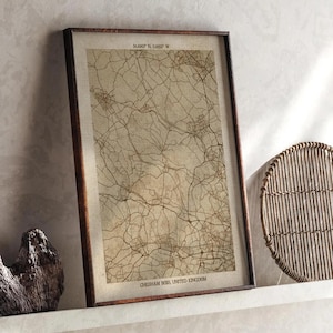 Op de afbeelding: Ingelijste vintage kaartprint van Chesham Bois, Verenigd Koninkrijk. De kaart, in bruine tinten, toont een netwerk van wegen en straten op een beige achtergrond. De lijst is donkerbruin.