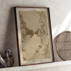 May include: Framed map print of Florianópolis, Brazil, in sepia tones. The map features detailed street and land outlines, with the city name and coordinates at the top and bottom. The frame is a dark brown color.