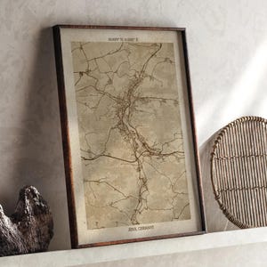 May include: Framed map print of Jena, Germany, in sepia tones. The map shows roads and city layout, with the text "Jena, Germany" at the bottom. The frame is dark brown.