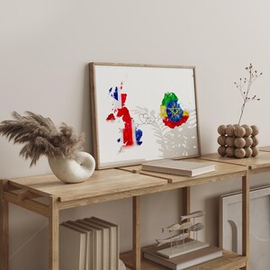 Może przedstawiać: Oprawiony wydruk przedstawiający akwarelowe mapy Wielkiej Brytanii i Etiopii, połączone cienką linią. Mapa Wielkiej Brytanii jest pokolorowana barwami Union Jack, a mapa Etiopii przedstawia flagę narodową. Grafika jest eksponowana na drewnianej półce.