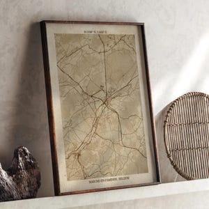 May include: Framed vintage map print of Marche-en-Famenne, Belgium, with coordinates at the top. The map is in sepia tones, with a dark brown wooden frame. The text "MARCHE-EN-FAMENNE, BELGIUM" is at the bottom.