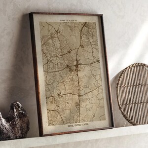 May include: Framed map print of Bowie, United States, with a brown frame. The map features a detailed network of roads and streets in a sepia tone. The text "39.0068° N, 76.7795° W" and "BOWIE, UNITED STATES" are visible.