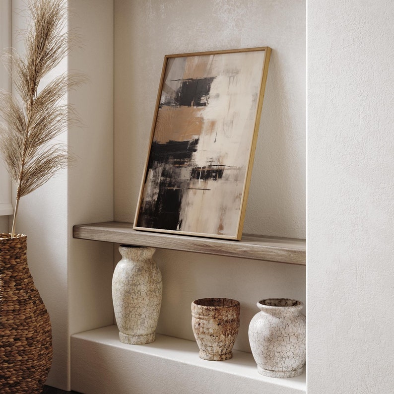 May include: A wooden shelf with three ceramic vases. The shelf is against a white wall and has a framed abstract painting above it. The painting is in shades of brown, black, and white.