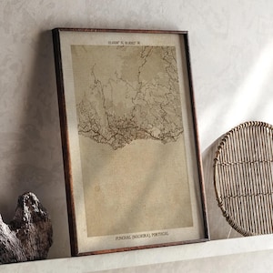 Könnte beinhalten: Gerahmter Vintage-Stil-Karten-Druck von Funchal, Madeira, Portugal. Die Karte in Sepia-Tönen zeigt detaillierte topografische Linien. Der Rahmen ist dunkelbraun. Koordinaten sind oben aufgedruckt, der Name der Stadt unten.