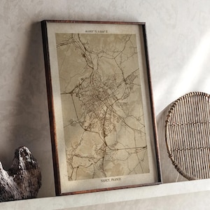 May include: A framed map print of Nancy, France, in sepia tones. The map details the city's streets and infrastructure. The frame is dark brown, and the print includes the coordinates 48.6921° N, 6.1844° E. The text "NANCY, FRANCE" is at the bottom.
