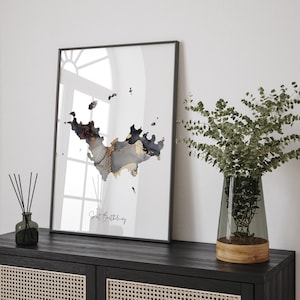 May include: A framed print with a black and gold abstract design of the island of Saint Barthélemy. The print is on a white background and has a black frame.