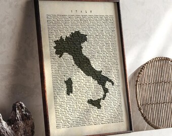 May include: A framed print featuring a map of Italy in a dark silhouette against a vintage-style background. The word "ITALY" is at the top. The print is in a dark brown frame, and the background is filled with text.
