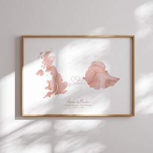 Może przedstawiać: Druk z mapą w kolorze różowym i złotym, wykonany w technice akwareli, z dwoma sercami łączącymi Wielką Brytanię i Etiopię. Tekst pod spodem brzmi: "Aaron & Brodie, Wielka Brytania & Etiopia, 10.08.2024".