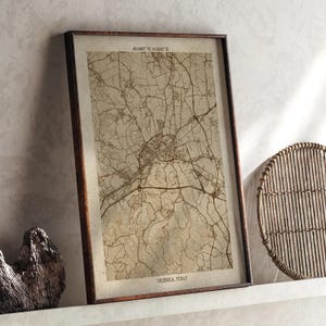 May include: Framed vintage-style map of Vicenza, Italy, in sepia tones. The map features intricate road and city details, with coordinates at the top and the city name at the bottom. The frame is dark brown.