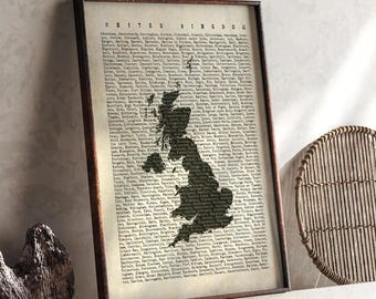 May include: Framed print of the United Kingdom, with a map silhouette in black against a vintage paper background. The text "UNITED KINGDOM" is at the top. The frame is dark brown. The print is displayed on a white shelf.