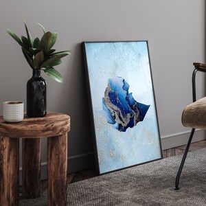 Może przedstawiać: Wydruk w ramie przedstawiający abstrakcyjny wzór w kolorze niebieskim i srebrnym, przedstawiający zarys Etiopii. Wydruk znajduje się na jasnoniebieskim tle z subtelnym efektem połysku.